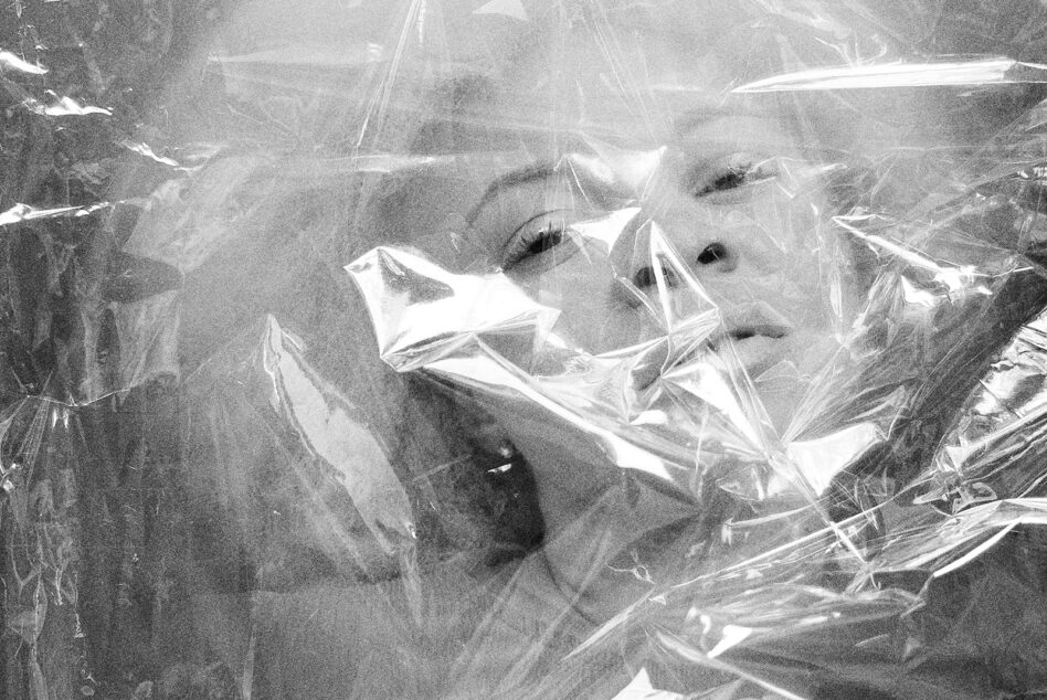 Black and white close-up faces wrapped in clear plastic film texture