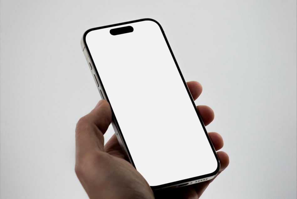 Hand holding smartphone with blank white screen against neutral background