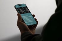 Hand holding iPhone displaying Inner.co teal website with BMX skateboarding imagery