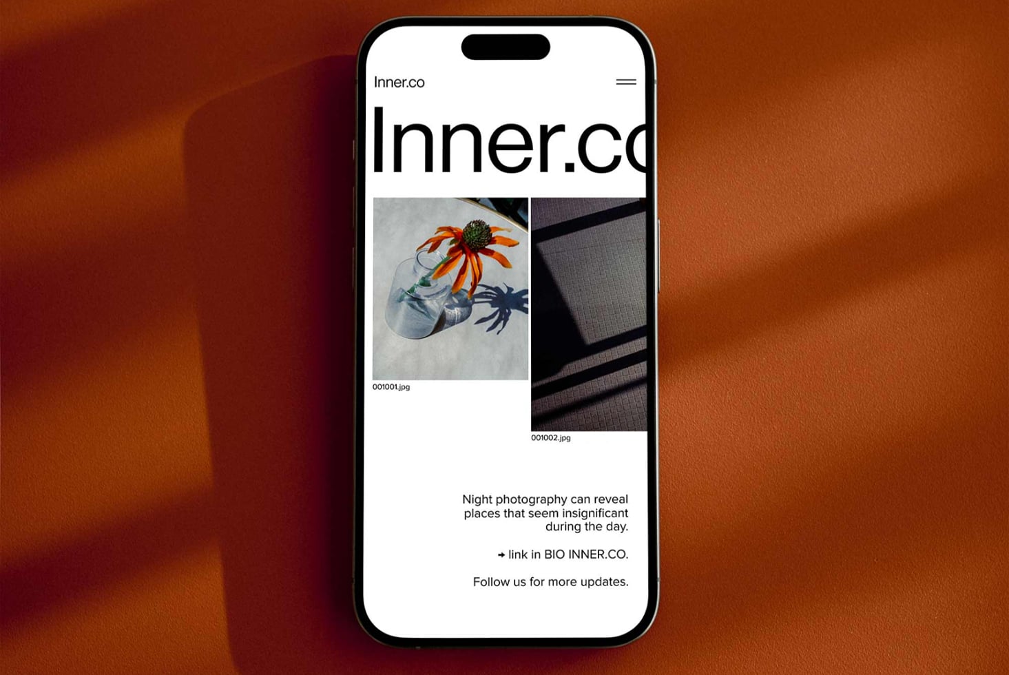 iPhone standing on rust circular table showing Inner.co website with portfolio gallery