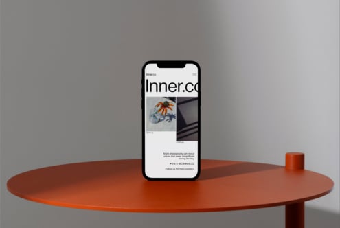 iPhone on terracotta table displaying Inner.co portfolio site with image grid layout