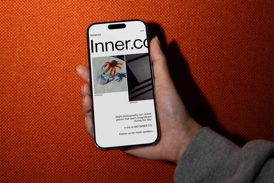 Hand holding iPhone with Inner.co website displaying night photography images on orange background