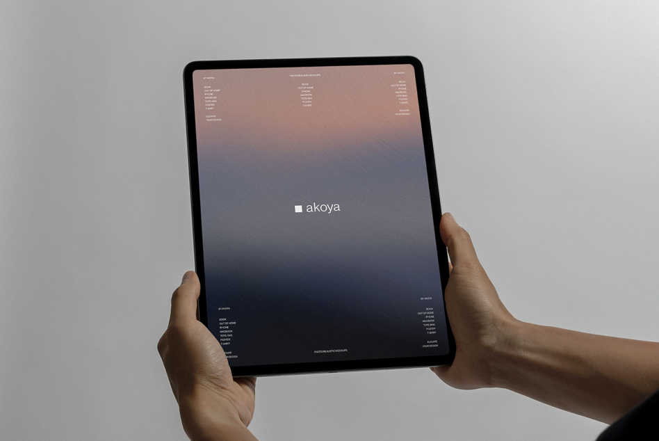 Hands holding tablet with gradient screen showing akoya branding