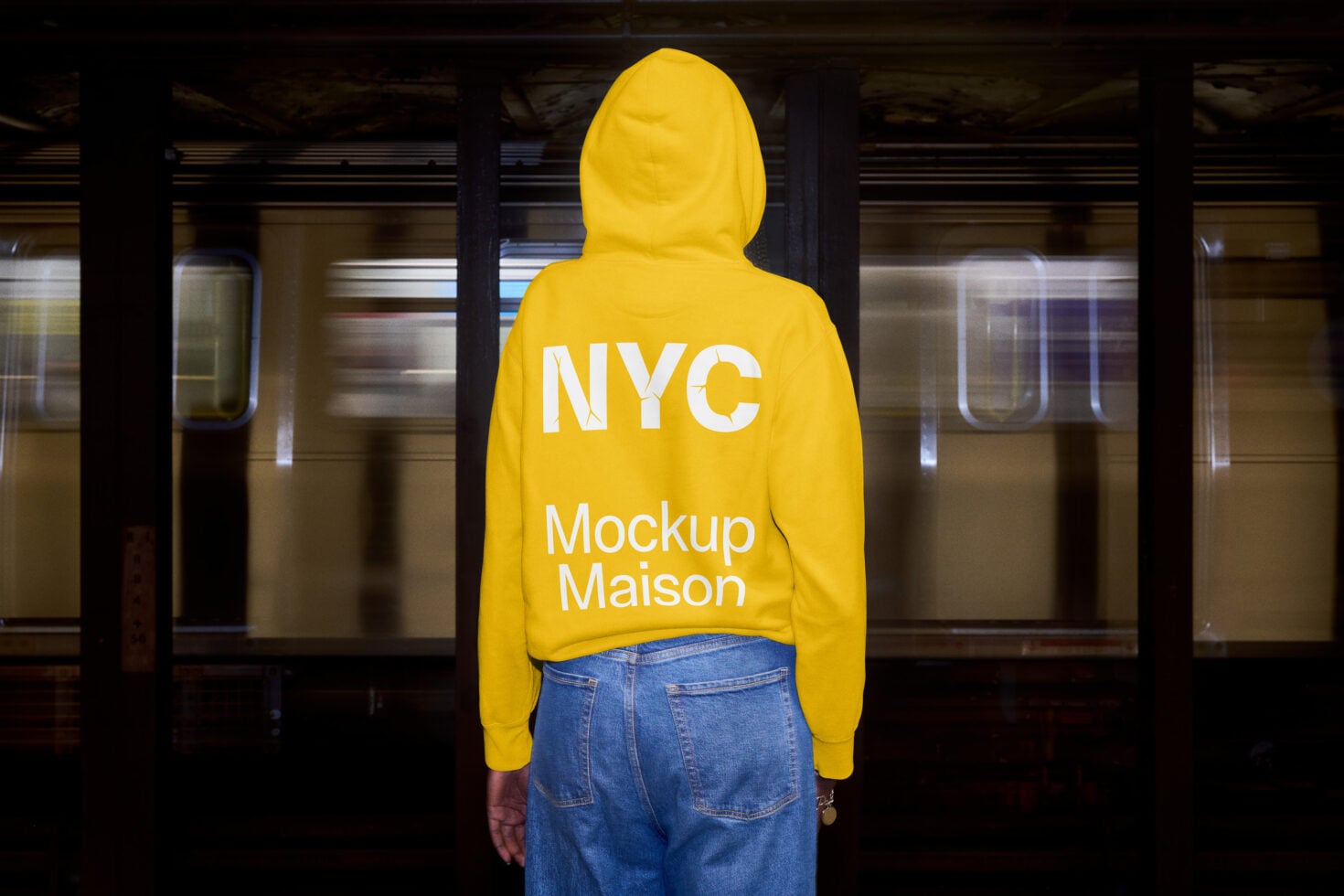 Person wearing yellow cropped hoodie from behind in industrial subway station