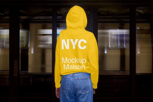 Person wearing yellow cropped hoodie from behind in industrial subway station