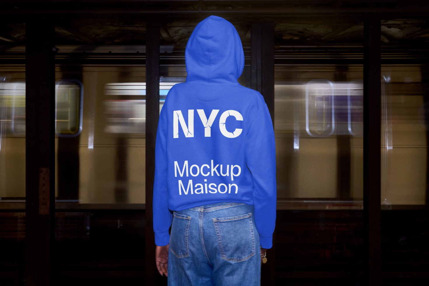 Person wearing bright blue hoodie from behind standing in subway station