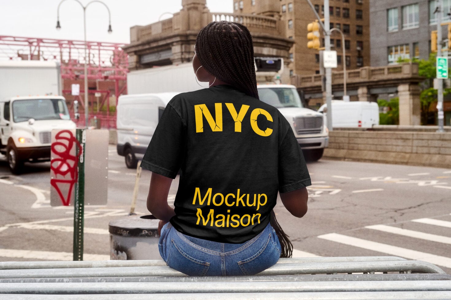 Woman on urban ledge wearing black tee with yellow NYC graphic back