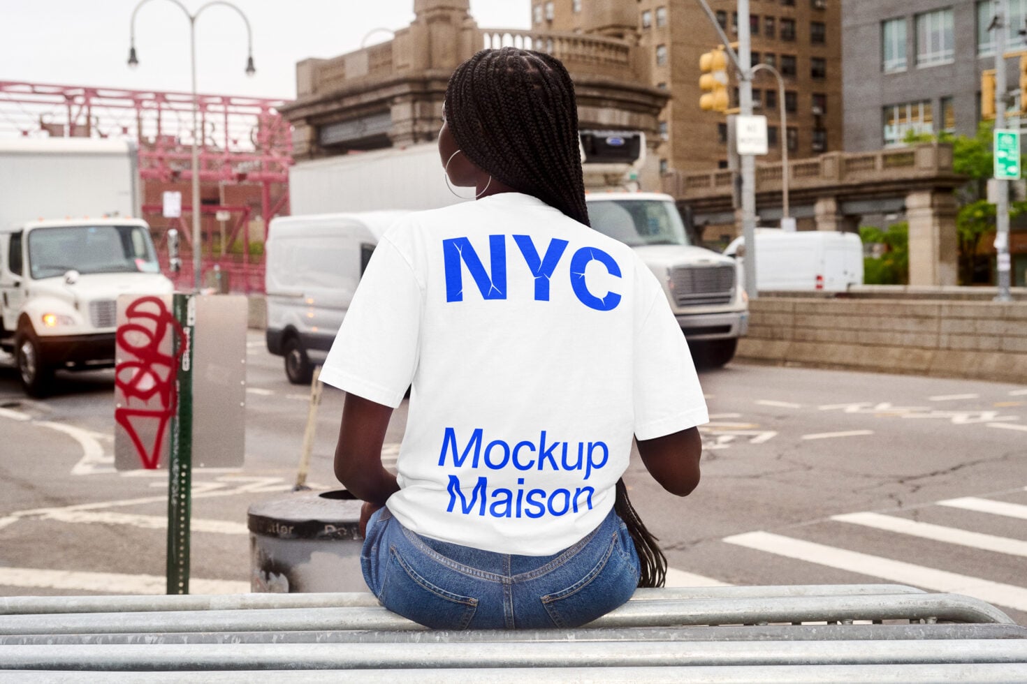 Woman sitting on urban ledge wearing white tee with blue NYC graphic back