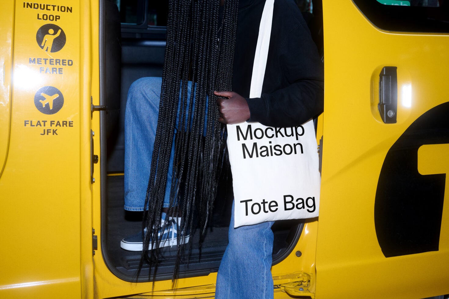 White tote bag mockup on yellow taxi door with jeans, braids, city backdrop