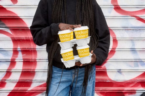 Stacked white egg carton mockups with yellow band held against red striped wall