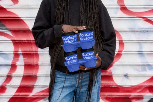 Two stacked blue egg carton mockups held by person in front of red white mural
