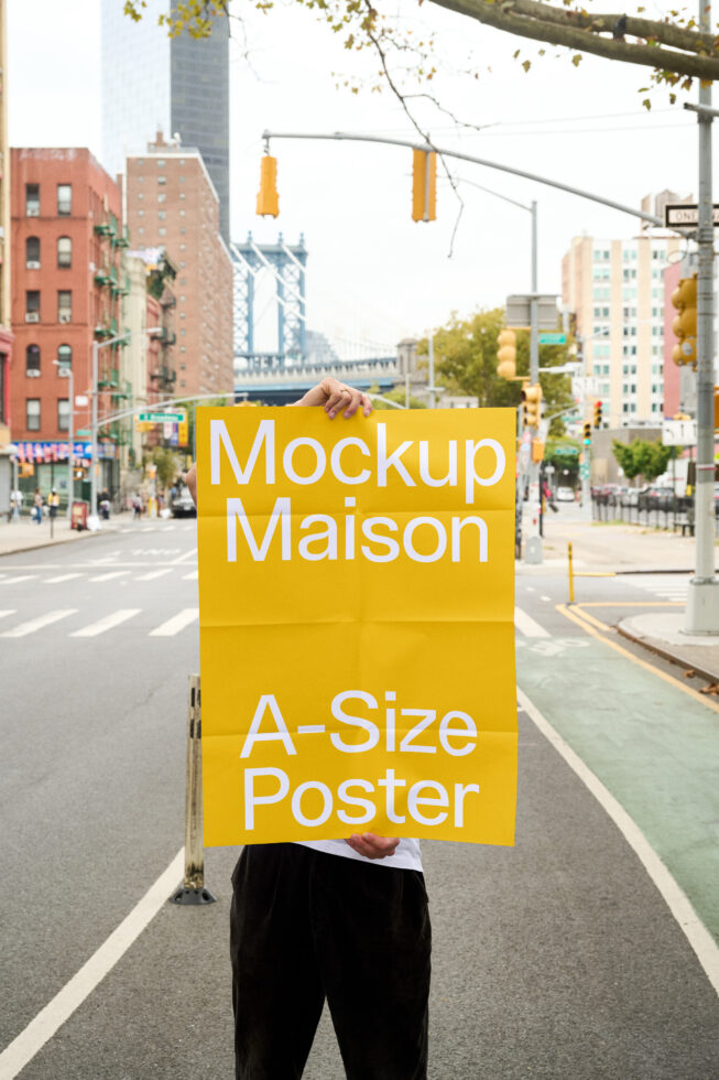 Yellow A-size poster mockup held on busy city street with Manhattan Bridge behind