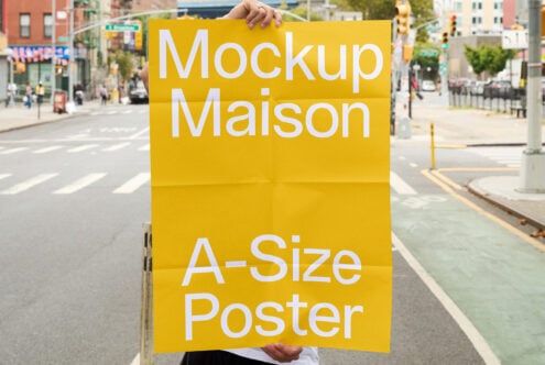 Yellow A-size poster mockup held up on downtown street with traffic lights