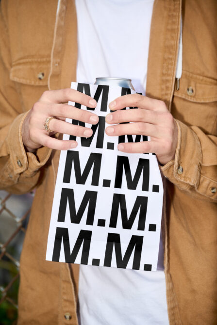 Can holder mockup with geometric pattern worn on beverage in tan jacket
