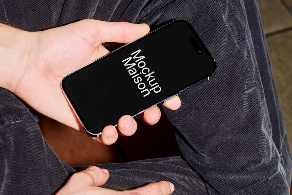 Hand holding iPhone with dark screen mockup against dark jacket