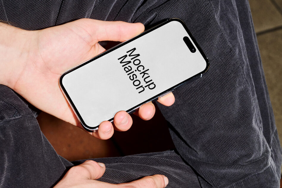 Hand holding iPhone with light screen mockup against dark jacket