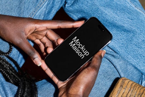Hands holding iPhone with black screen in front of light blue denim pants