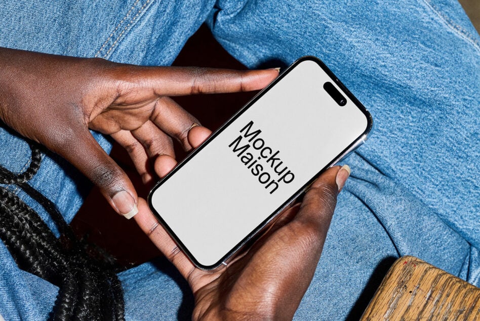 Hands holding iPhone with white screen in front of light blue denim pants