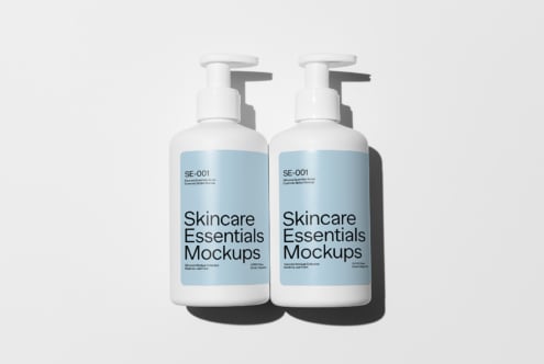 Two white pump bottles labeled Skincare Essentials Mockups on a white background. Ideal for designers seeking cosmetic branding presentations.