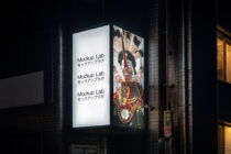 Corner light box at night showing white left panel with ornate cultural imagery on right side