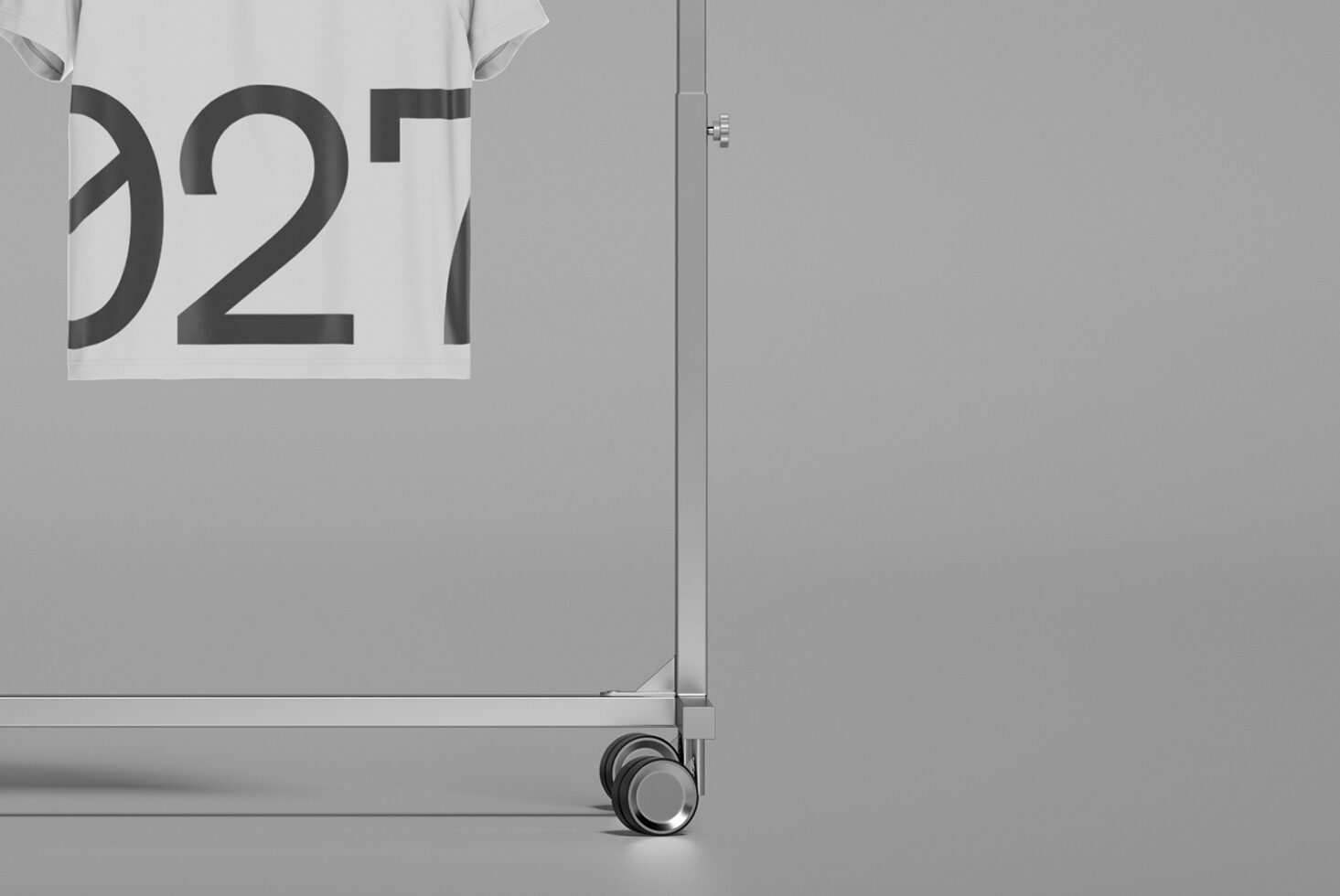 White tee on rolling rack showing large bold typography in minimal studio setting