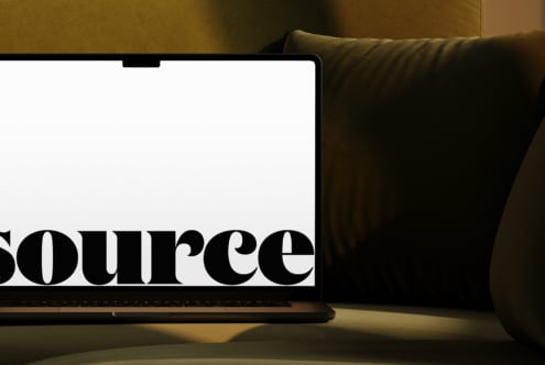 Laptop nestled in olive cushions with bold serif text on display