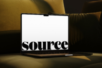 Open laptop on mustard couch showing serif font design mockup