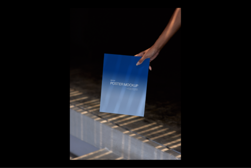 Person holds a blue poster mockup with shadows and reflections on a modern background. Ideal for showcasing poster designs. Perfect for graphic designers.