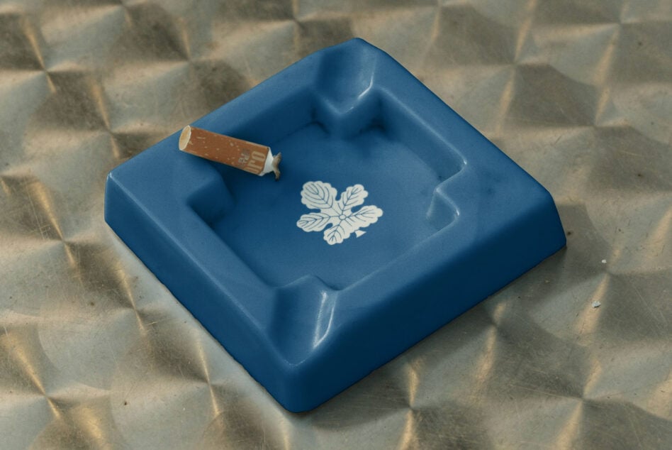 Blue ceramic ashtray with cigarette, white leaf motif printed in center square