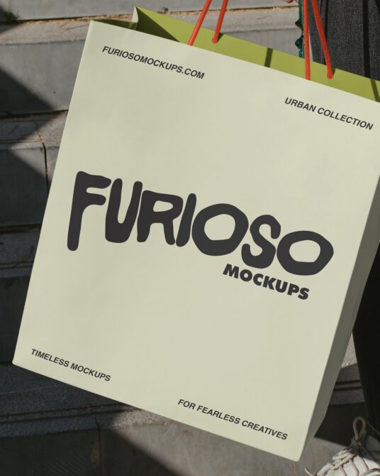 Cream paper bag with black Furioso Mockups text, red handles close-up view