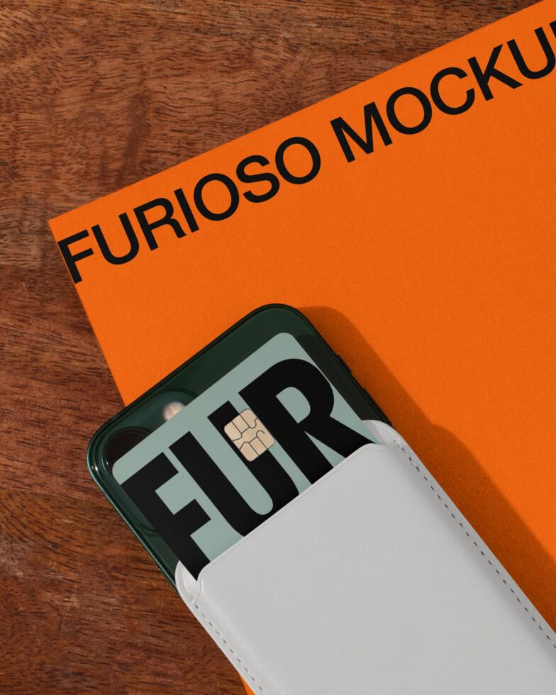 Phone in white case with card design on orange paper, wooden surface