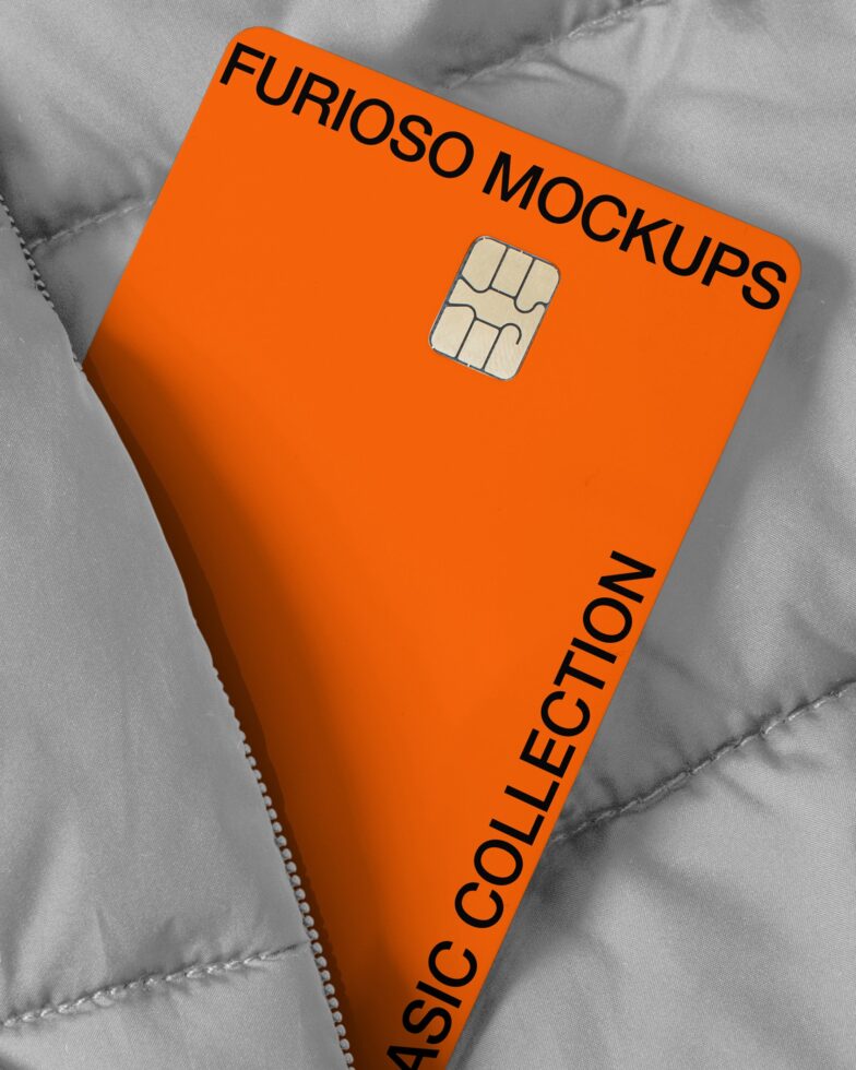 Orange credit card with Furioso Mockups text lying on quilted gray fabric