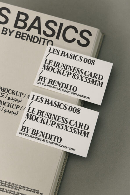 Two cream business cards stacked on white notebook with Les Basics branding
