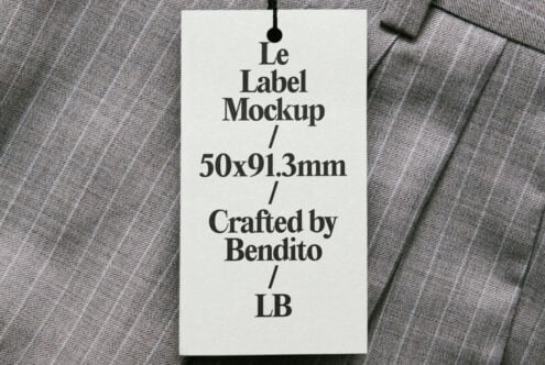 Cream hang tag on textured fabric with black cord showing Le Label Mockup text