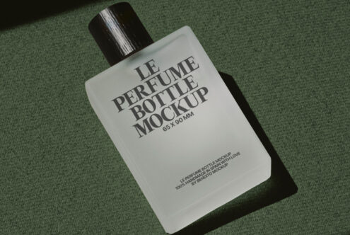 Flat lay of white rectangular perfume bottle with black atomizer on muted green fabric