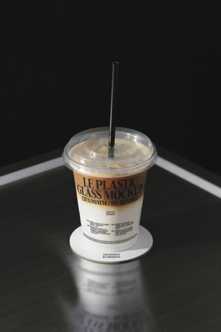 Iced drink in disposable cup with black straw, white coaster base