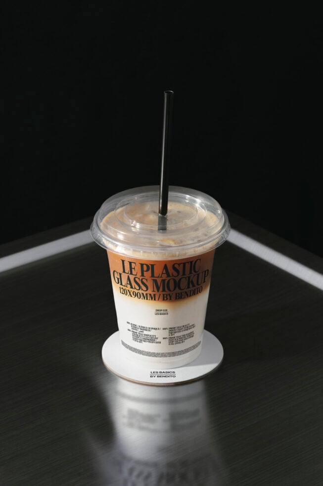 Iced drink in disposable cup with black straw, white coaster base