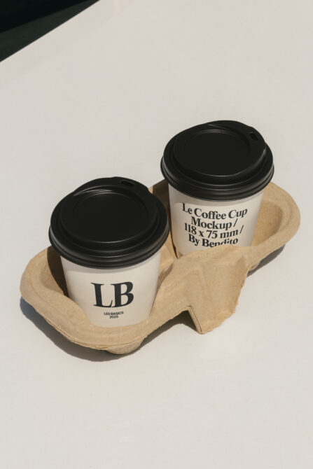 Two white coffee cups with black lids in cardboard carrier, LB branding on cups