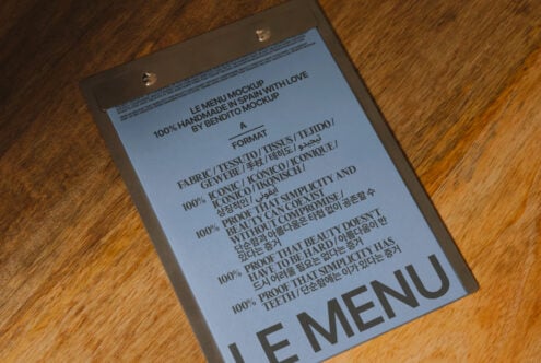 Blue menu mockup with metal clips on wood grain showing handmade typography