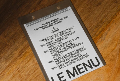 White menu mockup hanging from clips displaying multilingual content on timber