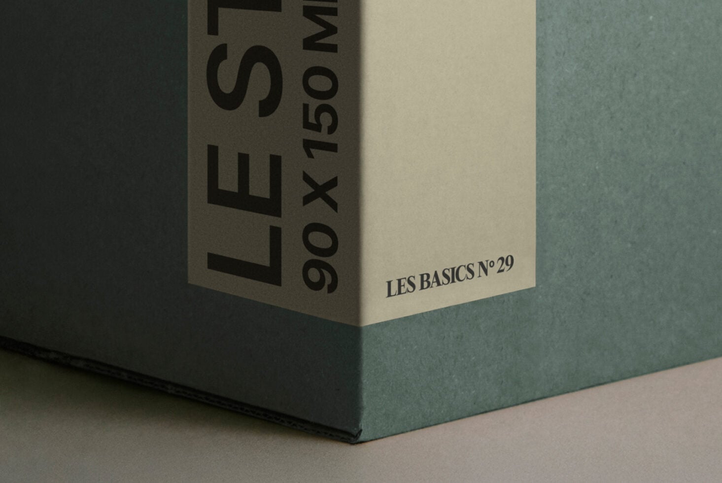 Close-up corner shot of white box with teal surface showing Les Basics branding