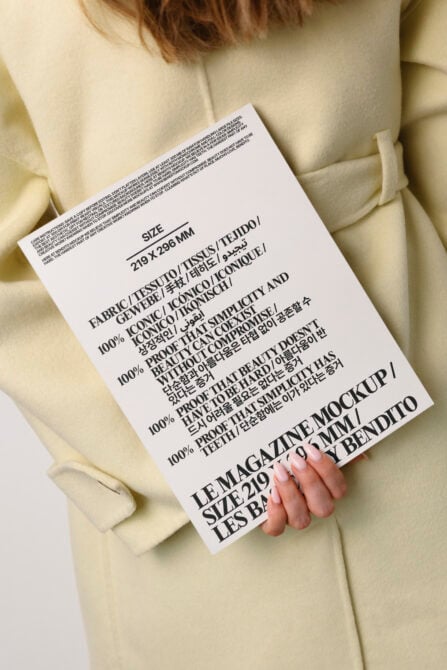 Magazine mockup with multilingual text held against cream oversized blazer