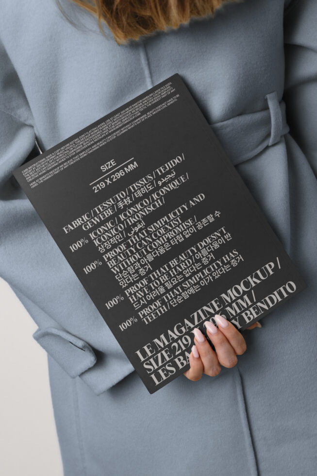 Magazine mockup with multilingual text held against gray oversized blazer