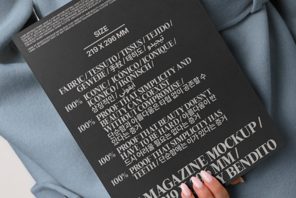 Dark magazine mockup with multilingual text held against blue-gray oversized blazer