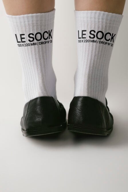 White ribbed crew socks on feet with black embroidered branding