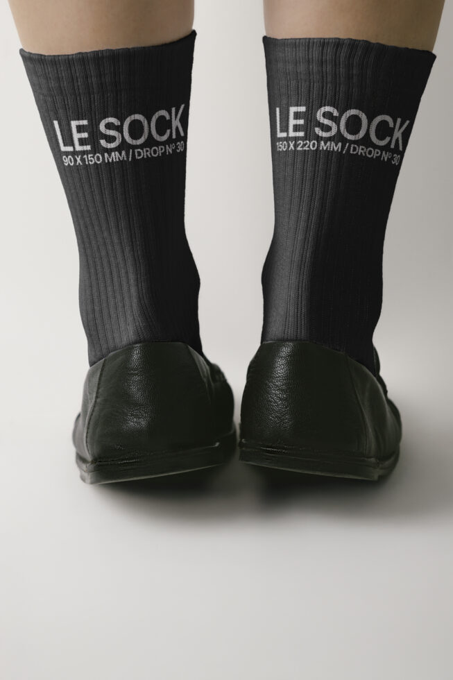 Black ribbed crew socks on feet with white embroidered branding