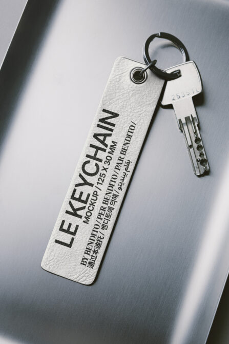 Off-white textured hotel keychain with black engraved text next to metal key