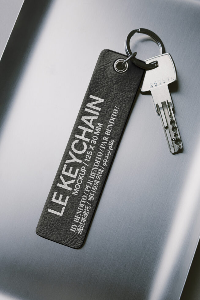 Black leather hotel keychain with silver engraved text next to metal key