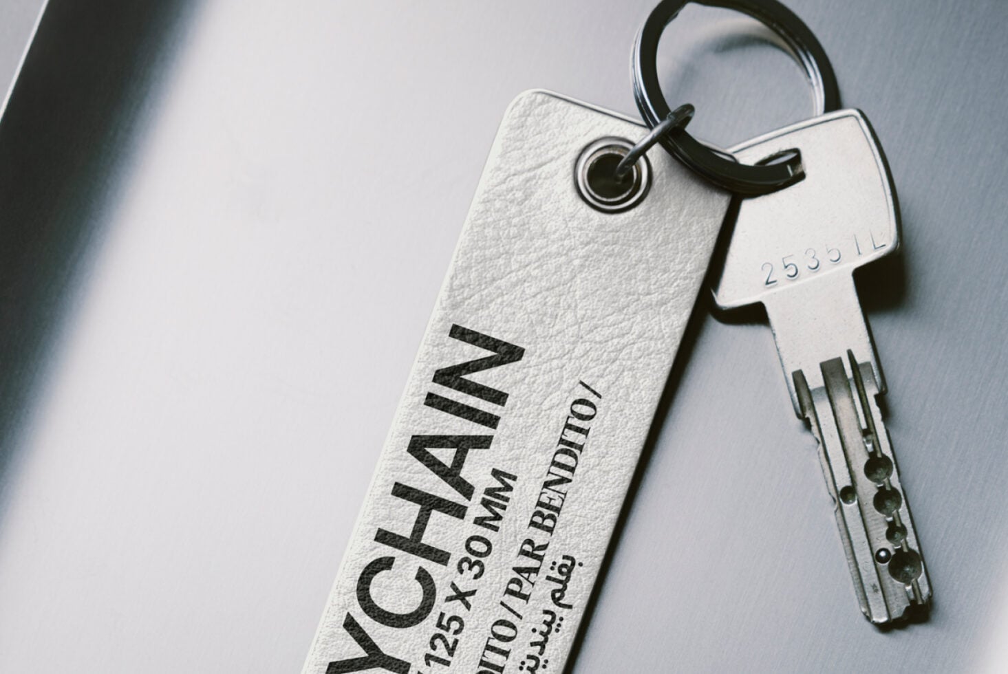 Light gray fabric keychain with black embossed lettering paired with metal key