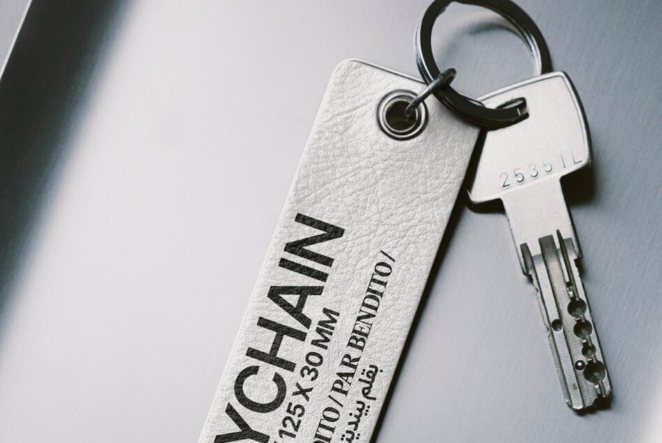 Light gray fabric keychain with black embossed lettering paired with metal key